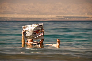Man reading a newspaper while floating on the Dead sea, Jordan, Asia