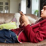 Teenage boy on sofa, listening to music